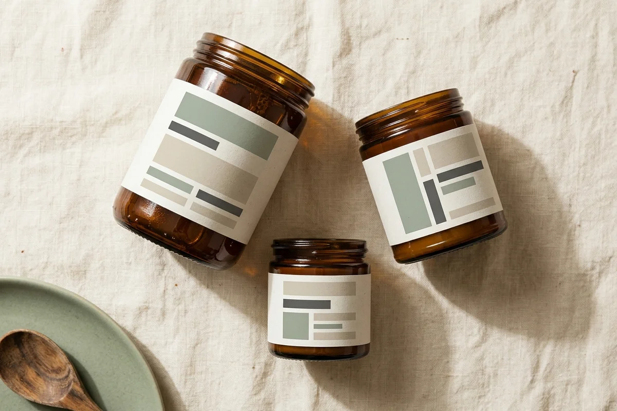 A clean overhead view of a packaged food jar on a warm neutral surface, with the front panel clearly showing both a fanciful product name at the top and a plain descriptive food name below it, editorial studio lighting